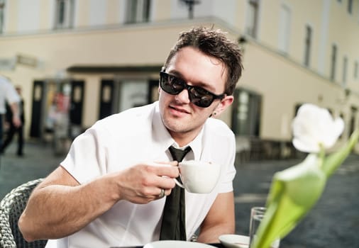 Cool young man drinking coffee in the city