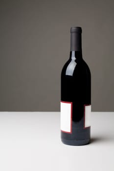 Unopened bottle of red wine on white table