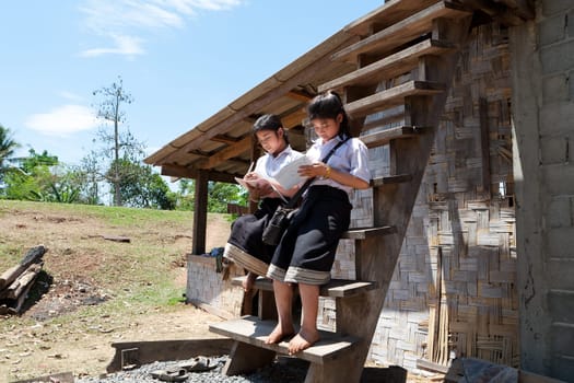 Female students from Asia,studying in front of the house outdoors