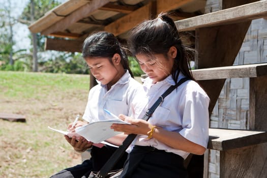 Female students from Asia,studying in front of the house outdoors