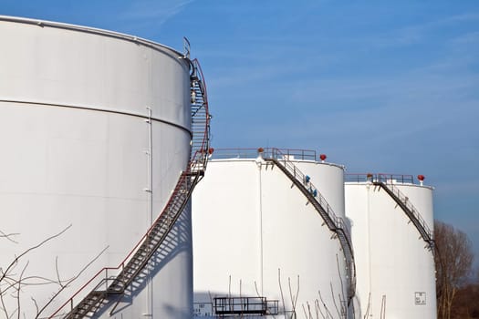 white tanks in tank farm with blue sky