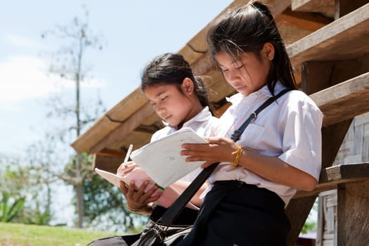 Female students from Asia,studying in front of the house outdoors