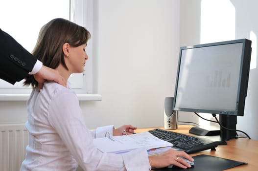 Business working person (woman) behind computer receiving neck massage from colleague (only hands visible)