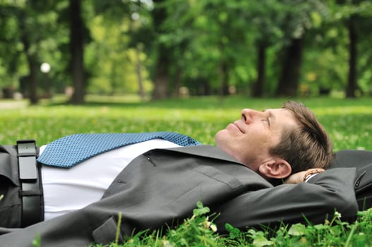 Senior people series - mature business man lying on grass and relaxing in park