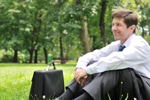 Senior people series - mature business man siting on grass and relaxing in park