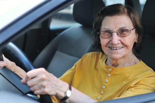 Active senior woman - smiling retired lady driving car, detail