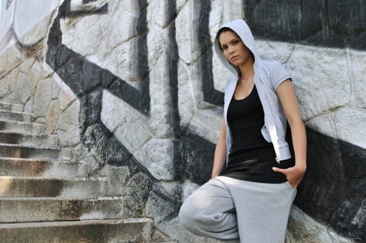 Young person (teenage girl) in hip hop style posing in front of black and white graffity wall