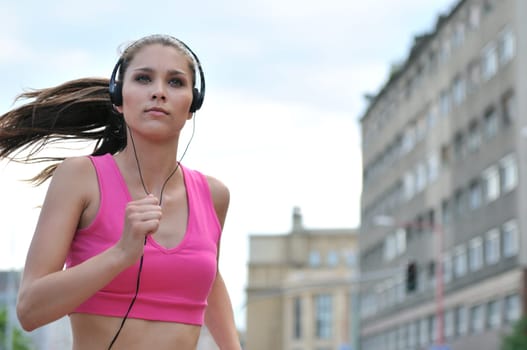 Person (young beautiful woman) listening music running (jogging) in city street