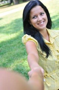 Young smiling woman stretching her hand and receiveing help