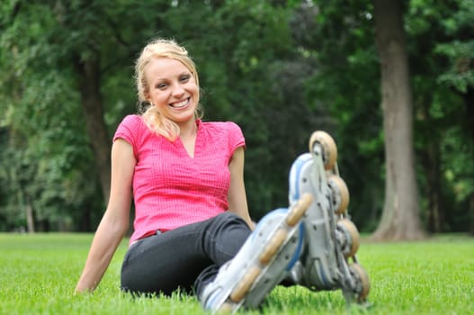 Young smiling woman relaxing in green grass after roller blading