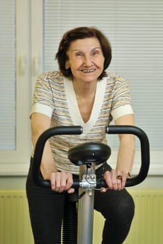 Mature fitness woman exercise on spinning bicycle at home