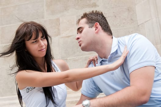 Young couple having relationship problems - woman refuses kissing from man