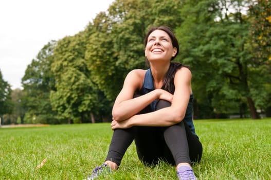 Young happy smiling woman looking up siting in grass
