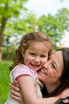 Portrait of small cute girl enjoying life with her mother outdoors