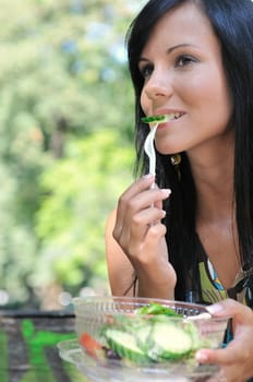 Young beautiful woman having lunch break and eating salad outdoors in park