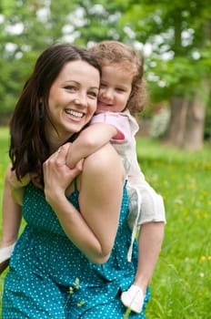 Small girl enjoying life with her mother outdoors - carrying on back