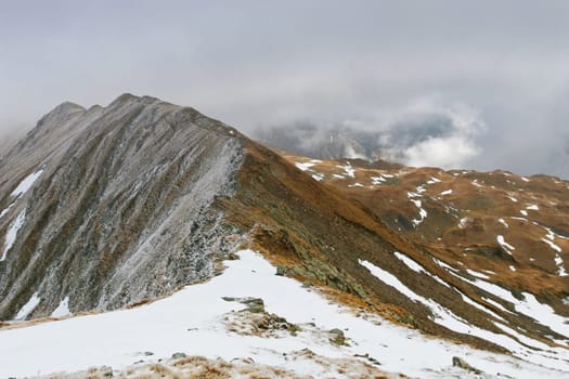 traces of snow on a mountain in clouds