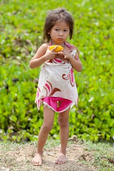 Portrait of girl from Asia,child in poor clothes eating mango