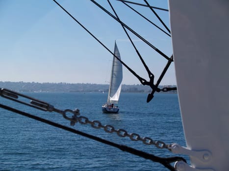 Sailboat as seen through the ropes of the “Star of India” that is moored at the “Maritime Museum” in San Diego, California.