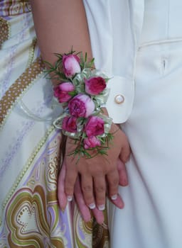 Pink rose wrist corsage with babies breath and green and white ribbons.