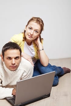 Young man and woman with laptop computer lying on the floor