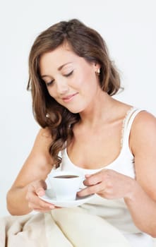 Pretty young woman waken up and having coffee in her bed