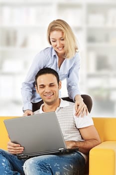 Happy young man and woman sitting together and looking at computer screen