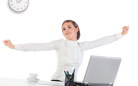 Pretty young businesswoman stretching her hands while sitting at her desk