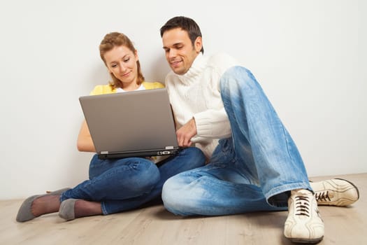 Young happy woman and man sitting together with laptop computer