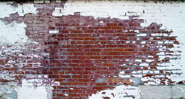 Grungy, weathered brick wall with barred windows, on the back of an old historic building, that has pealing paint and some tuck point renovation done.