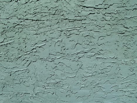 Rough textured concrete or stucco exterior wall painted green.