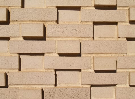 A light colored, beige multi-layered and multi-sized brick wall.