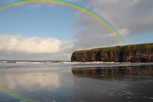 a view of the beach cliffs in ballybunion co kerry ireland with rainbow reflection on a wet stormy day