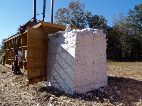A module builder driving away and leaving a completed cotton module in the field.
