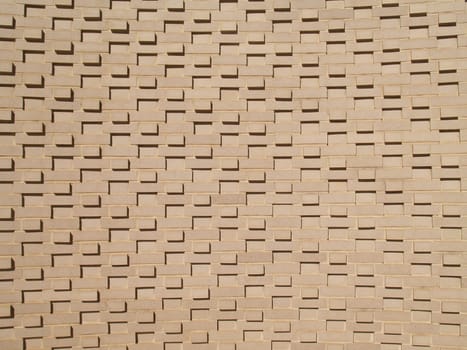 A light colored, beige multi-layered and multi-sized brick wall.