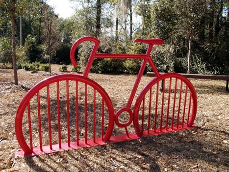 Red bike rack in a park shaped like a bike.
