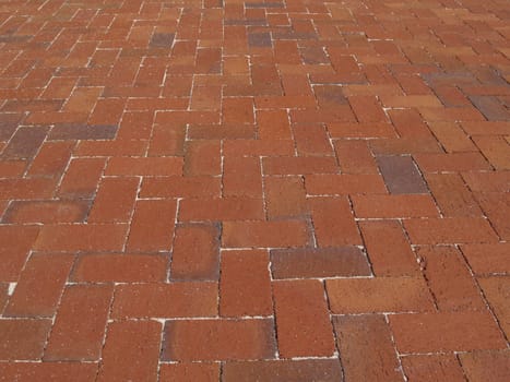 Multi-colored Red brick sidewalk laid in a herringbone pattern.