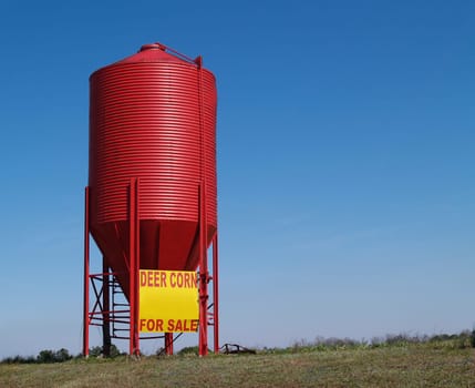 Small red grain silo used to sell corn for deer with copy space.