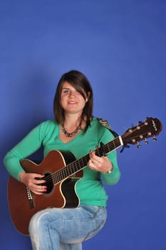 young woman standing and playing guitar