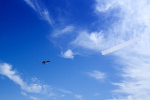 Small airplane pulling a blank sign for advertisements