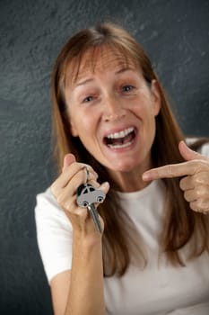 happy young woman to point at her own car key and car on a key ring in the hand
