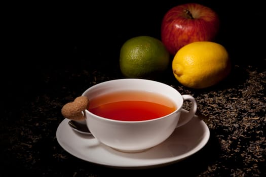 mug of tea with a saucer and sugar heat on black background