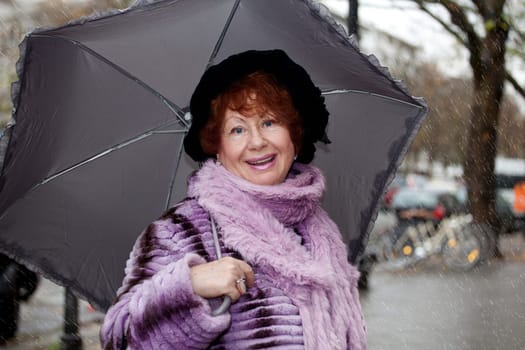 Senior woman Laughing standing in front with umbrella, street background