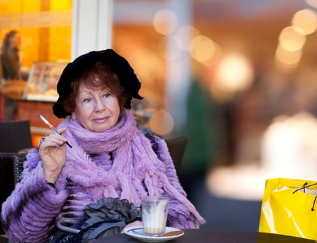 cheerful old Woman drinking coffee and smoking in a restaurant