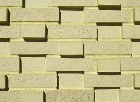 A pastel yellow multi-layered and multi-sized brick wall.