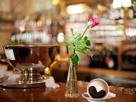 Rose and coffee cup with heart made of coffee grounds at the bar