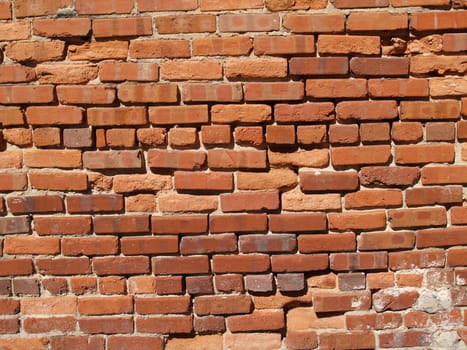Old weathered wall with red multi-sized brick and a patched area.