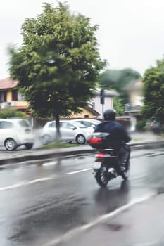 Man riding motorcycle in the rain on road.