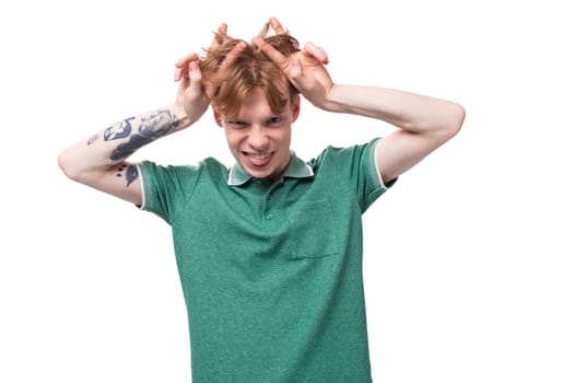 young emotional caucasian man with red hair dressed in a green t-shirt shows his coolness against the background with copy space.