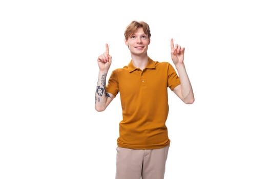 portrait of a young guy with short red hair dressed in a summer T-shirt pointing his hands up.